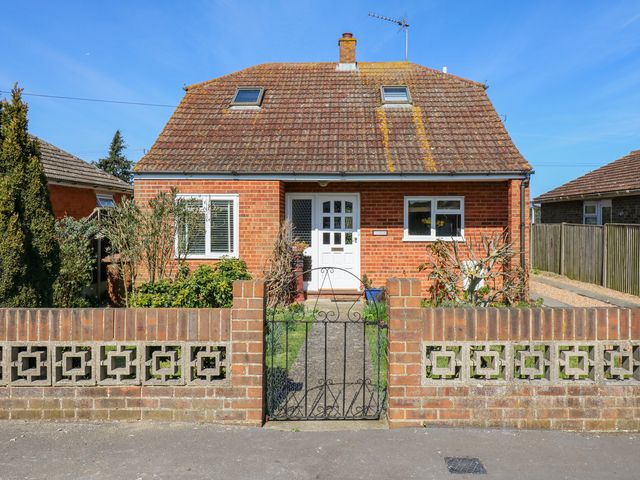A brick house with a tiled roof two skylight windows a front door and a small garden behind a low brick wall at Twynholm in Leysdown-on-Sea near Warden