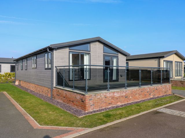 A modern single story house with glass balcony on brick base in a residential area at Number 43 The Poplars Burnham Market