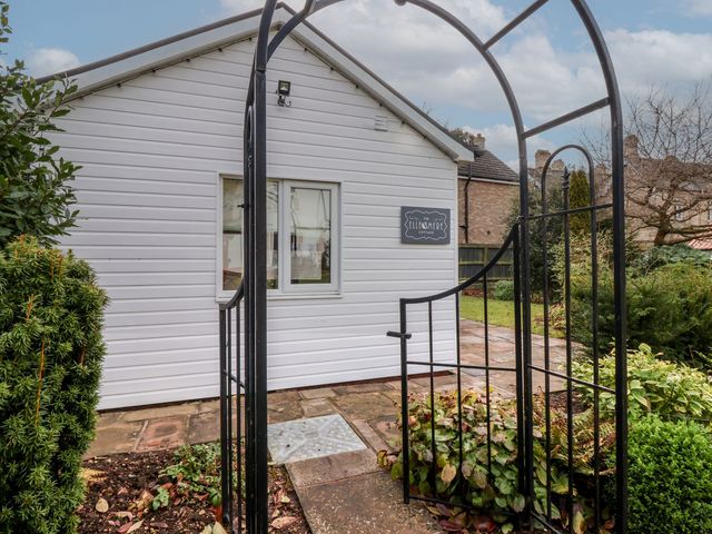 A garden gate leading to a white cottage with a sign that reads Ellesmere Cottage in Hornsea