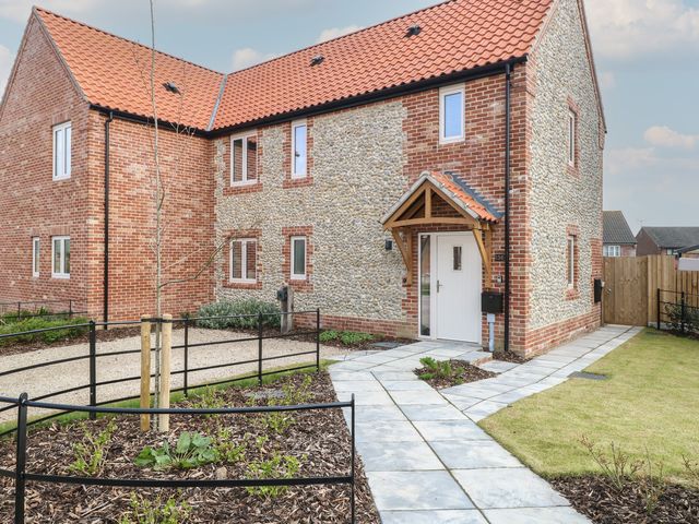 The front exterior of a brick and stone house with a tiled roof and paved walkway at The Hideaway Cromer in Northrepps near Overstrand