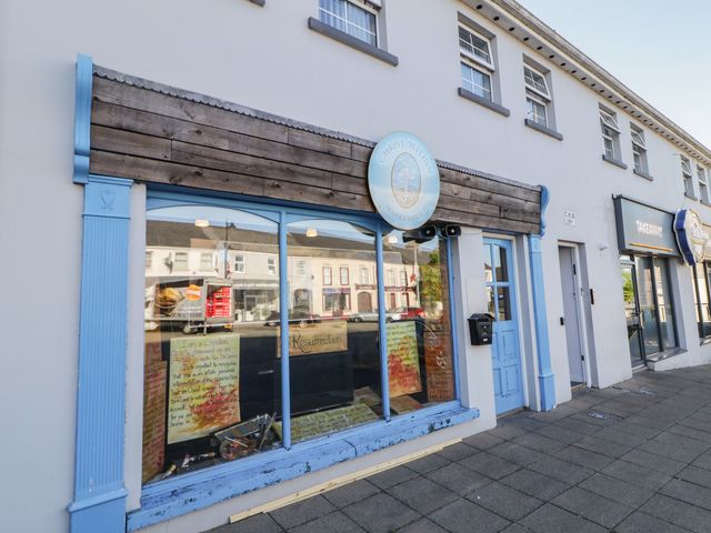 Exterior view of a building with a blue door and window displaying signs and a round sign that reads Christ Within Markethill