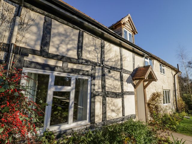 A half timbered stone house with windows a wooden door canopy and plants outside at Little Cowarne Court in Little Cowarne near Bromyard