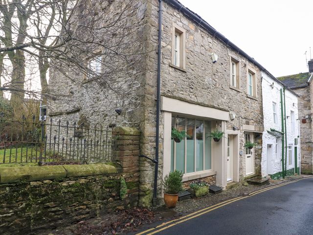 A stone cottage with plants outside on a narrow street in Grassington Wharfedale