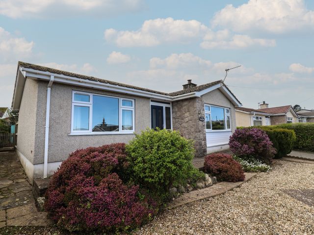 A single story house with bushes and gravel in the front garden at Bryn Eithin in Benllech near Red Wharf Bay