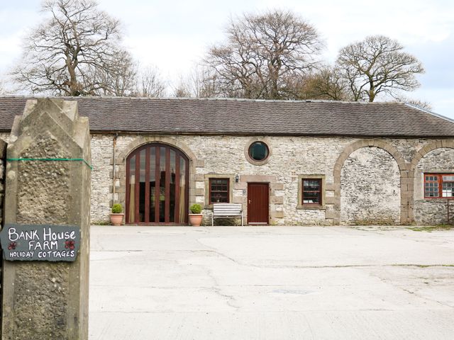 Stone building with large arched window small door and windows and a sign saying Bank House Farm Holiday Cottages at Number 3 in Biggin