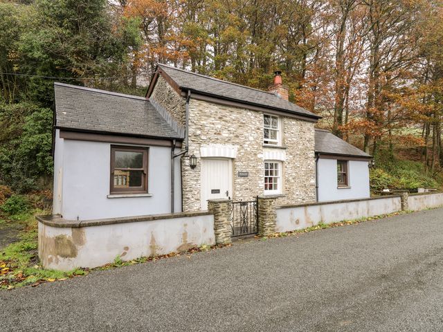 A stone cottage with two windows a white door and a small gated wall in front at Penlon in Capel Bangor near Aberystwyth