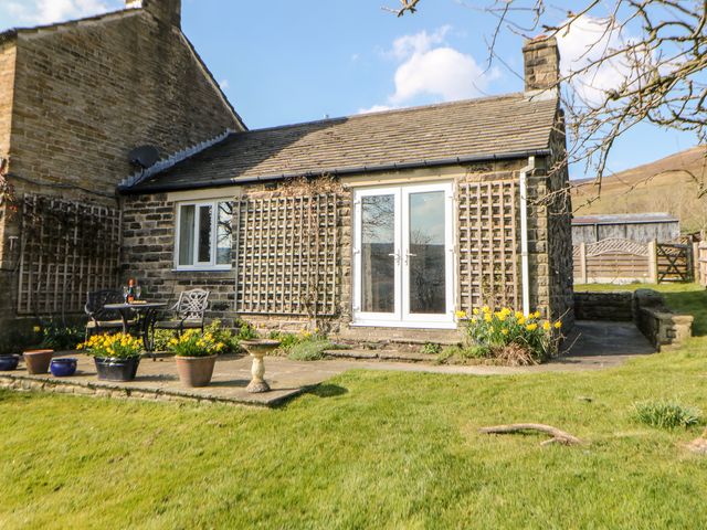 The exterior of a stone cottage with a patio table and chairs and potted plants in a garden at Hathaway Cottage in Edale