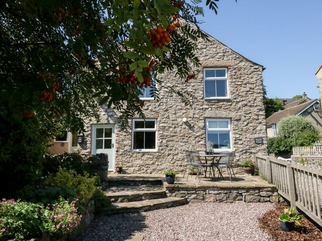 A stone house with a patio table and chairs surrounded by plants and a gravel pathway at Field View Bradwell near Castleton