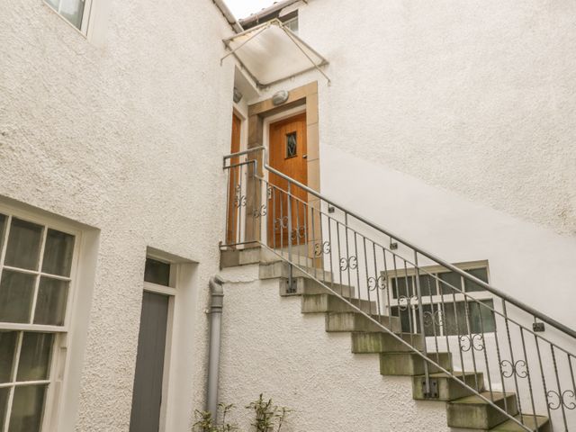 An exterior stairway with metal railing leading to a wooden door on a white textured building at Hayloft in Pittenweem
