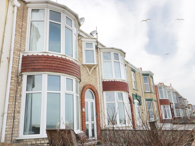 Row of houses with bay windows and brick facades under a cloudy sky at Number Fifteen in Withernsea