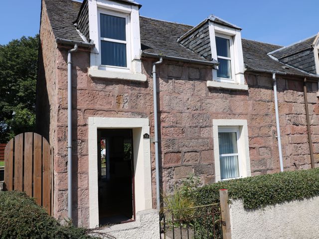Exterior view of a stone house with two dormer windows a door window and a garden gate at Witchelm House in Inverness