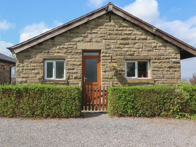 A stone house with two windows a wooden door and a hedge in front at Bridge End in Worston near Downham