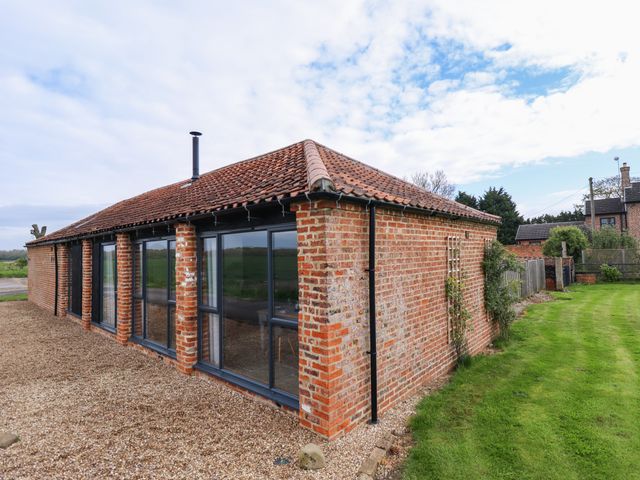 An exterior view of a single-story brick house with large windows a gravel path and a lawn at Little Owl in Market Rasen