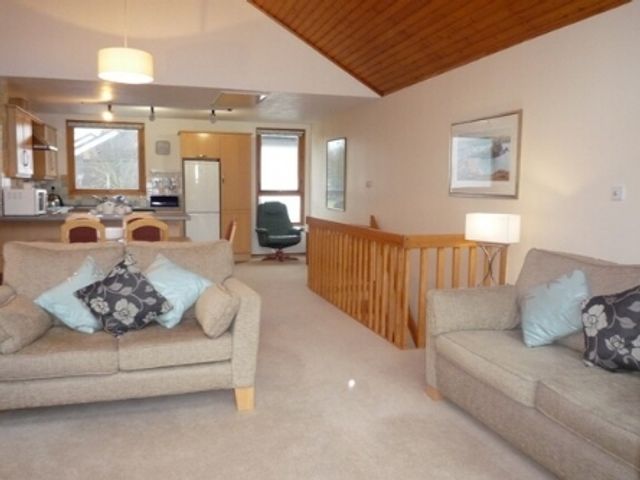 An open living room with two sofas and a kitchen in the background at 19 Keswick Bridge in Keswick