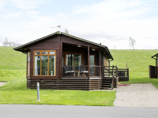 A wooden cabin with a porch and chairs surrounded by grass at 16 Badgers Retreat in Richmond