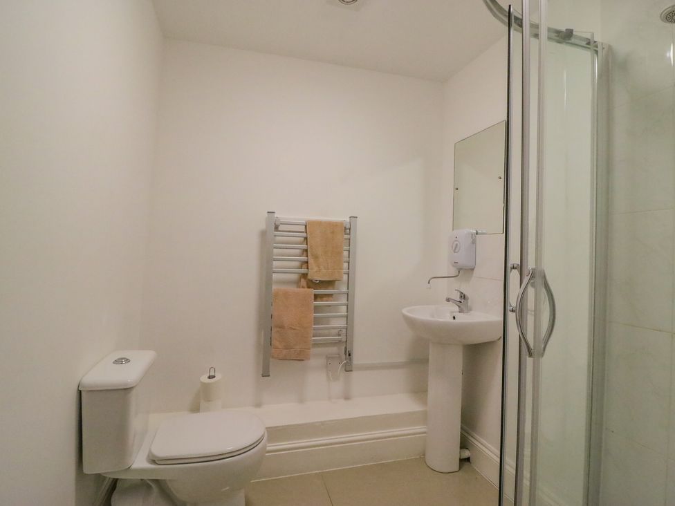 A bathroom with a toilet, sink, towel rack with towels, and a glass shower enclosure at Butcombe Farm House in Butcombe