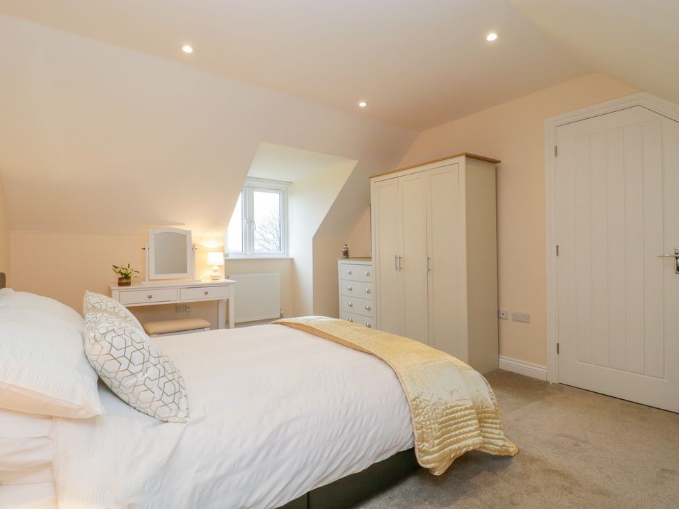 A bedroom with a bed a wardrobe a chest of drawers and a dressing table at The Donkey Shed in Sherborne