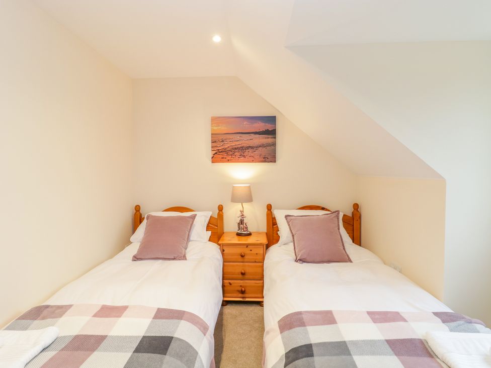 A bedroom with two single beds a wooden nightstand and a lamp at The Donkey Shed in Sherborne