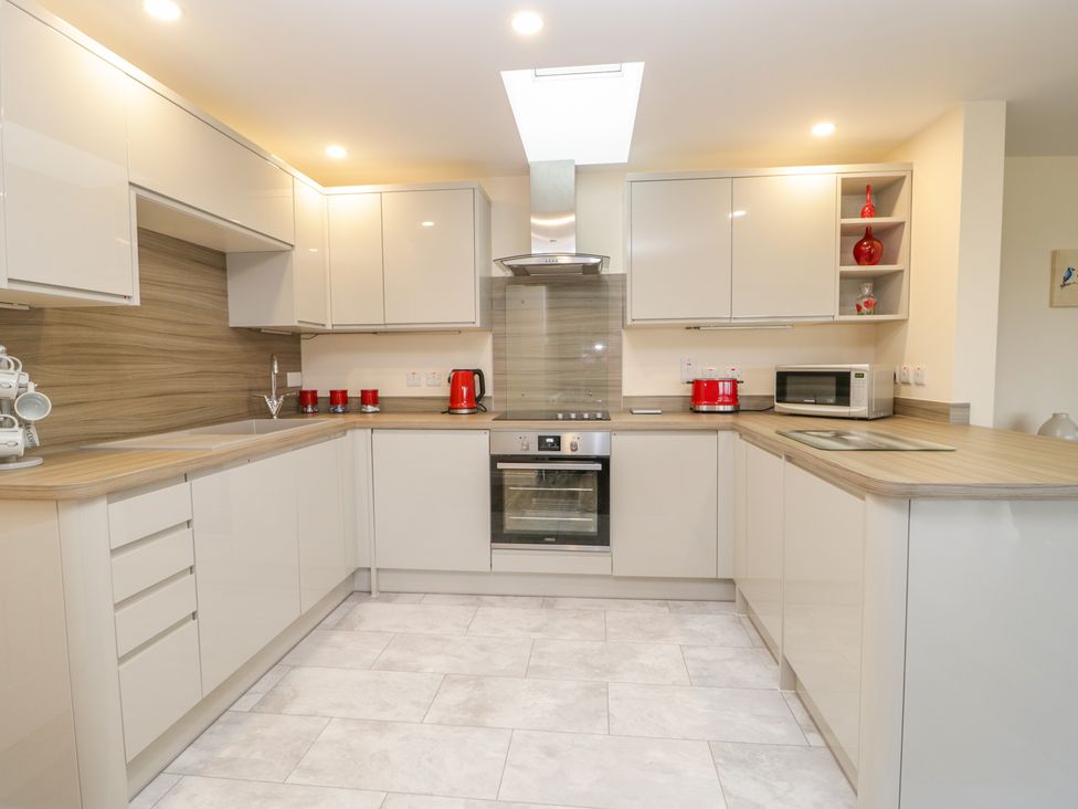 A modern kitchen with white cabinets wooden countertops and red kitchen appliances at The Donkey Shed in Sherborne