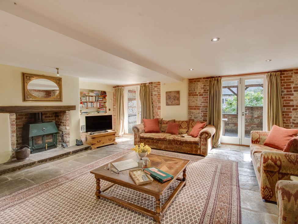 A living room with sofas around a coffee table and a fireplace at Manor Farm Barn in Dewlish
