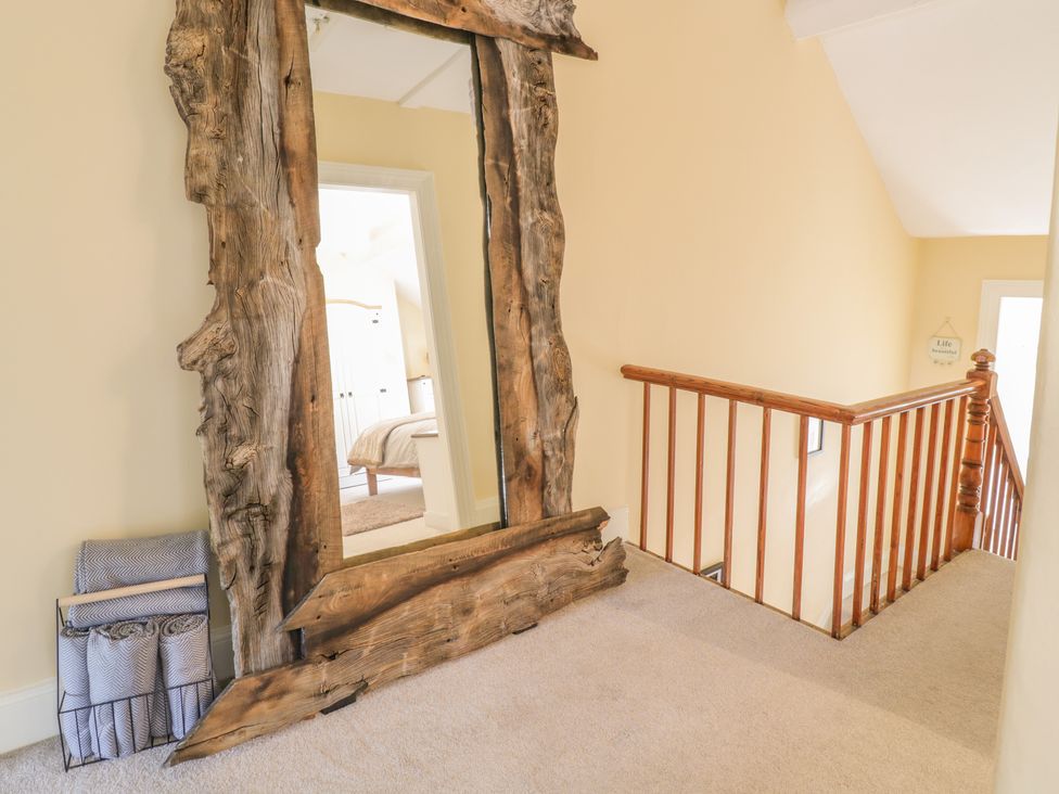 A hallway with a wooden framed mirror and a metal stand holding folded blankets at Angorfa in Llanbedr