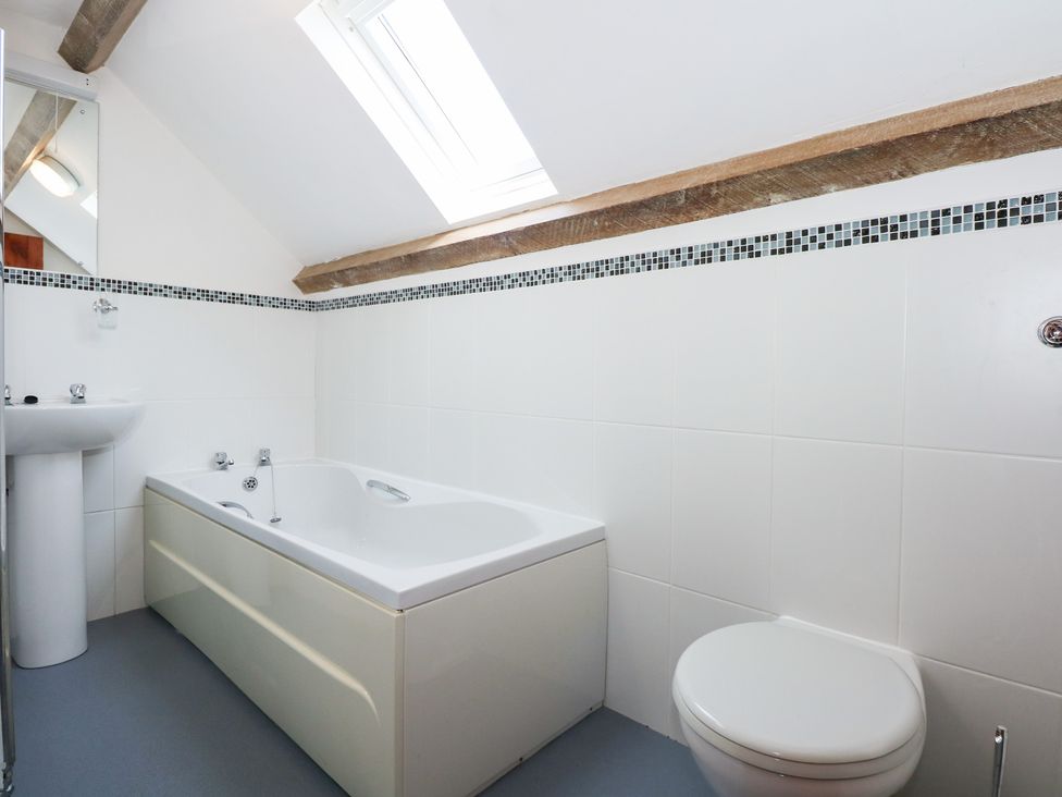 A bathroom with a bathtub sink and toilet under a skylight at Hafod in Pontllyfni