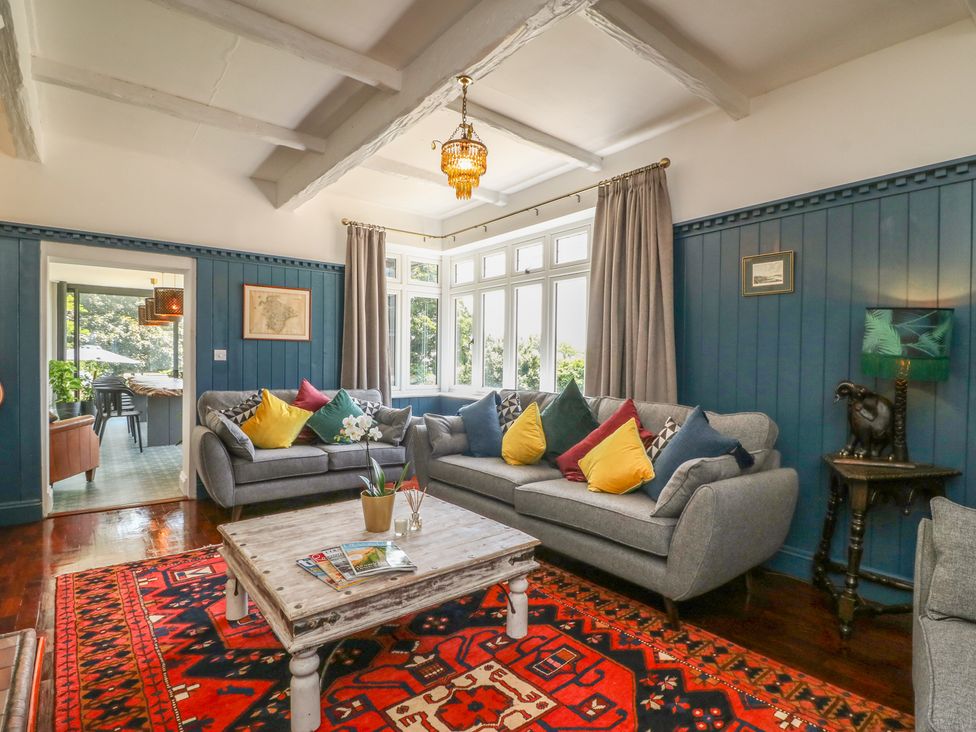 A sitting room with gray sofas colorful cushions a wooden coffee table and a red patterned rug at The Coach House in Teignmouth