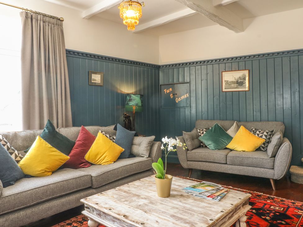 A living room with two grey sofas with colorful cushions and a wooden coffee table at The Coach House in Teignmouth