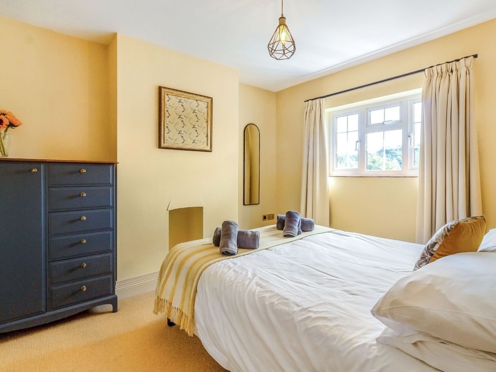 A bedroom with a bed towels dresser and window with curtains at Ivet Lowe Hopton near Wirksworth