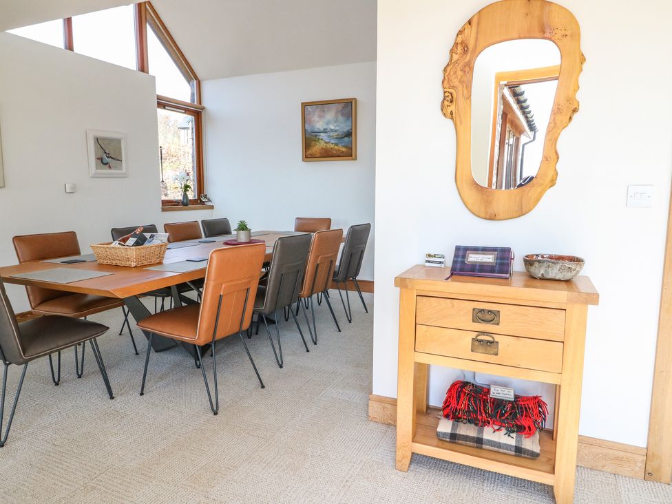 A dining area with a table and chairs next to a wooden drawer with a mirror above at Balvaig in Pitlochry