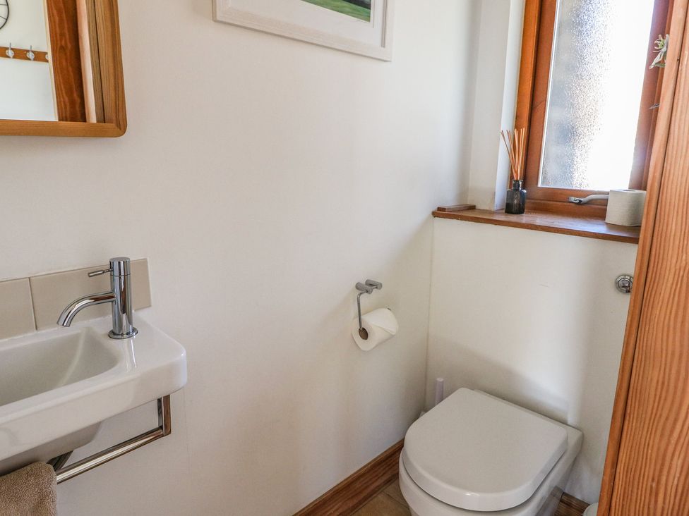 A small bathroom with a toilet a sink with a faucet a window and a mirror at Balvaig in Pitlochry