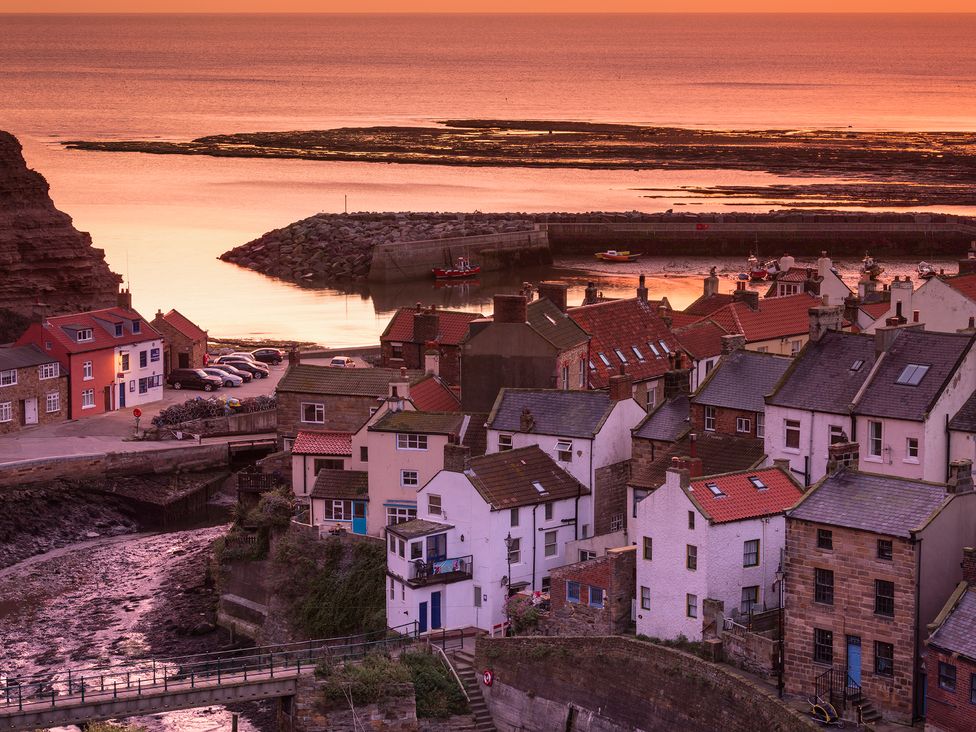 A coastal village with houses near a harbor at sunset at Roxby Cottage in Staithes