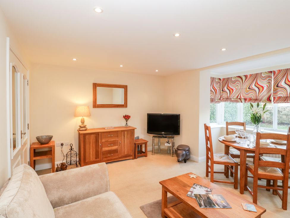 A living room with beige sofa wood furniture dining table and TV at Mayflower in Swanage