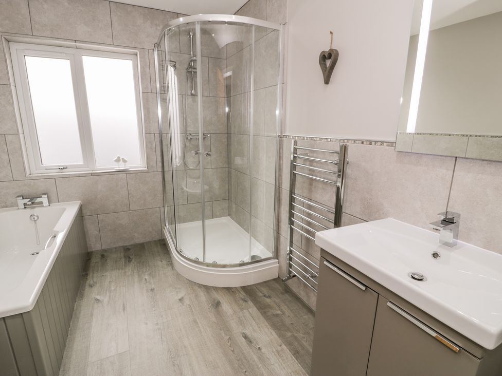 A bathroom with a bathtub shower cubicle sink and towel rack at Cartref in Trawsfynydd