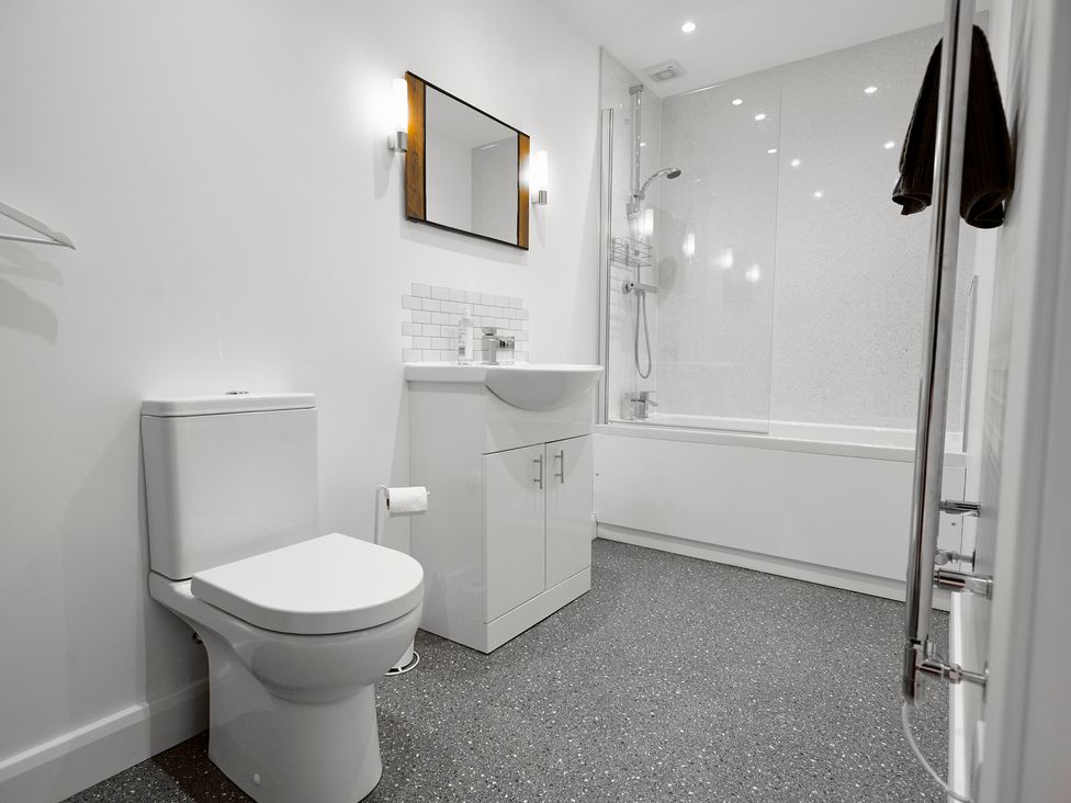 A bathroom with a toilet sink cabinet mirror bathtub and shower at Whernside Lodge in Rathmell near Settle