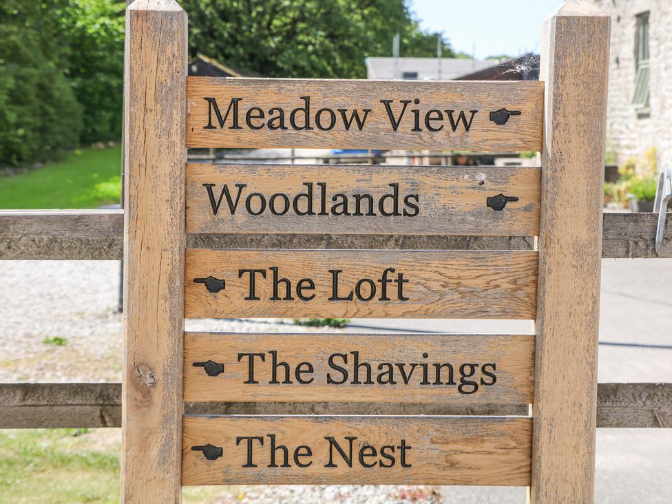 A wooden signpost with names Meadow View Woodlands The Loft The Shavings and The Nest in Buxton