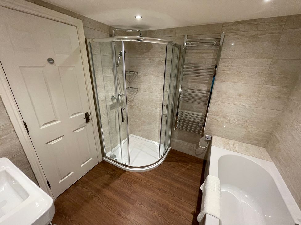 A bathroom with a shower enclosure a bathtub a washbasin and a door at Victoria Mount in Grange-Over-Sands
