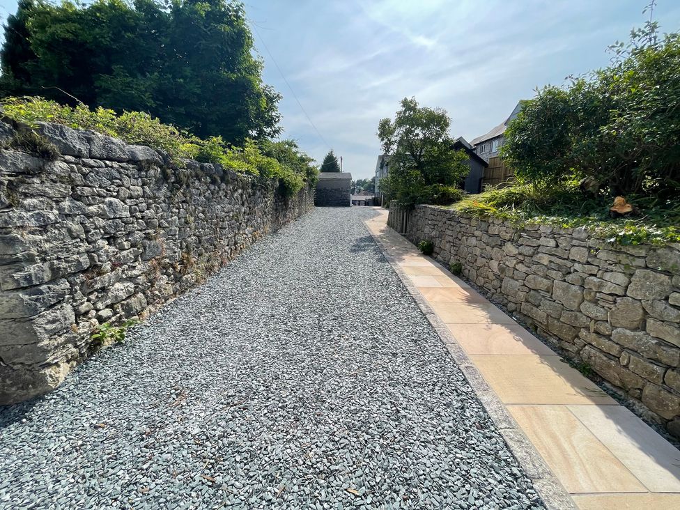 A gravel driveway with a stone retaining wall and a paved walkway at Victoria Mount in Grange-Over-Sands