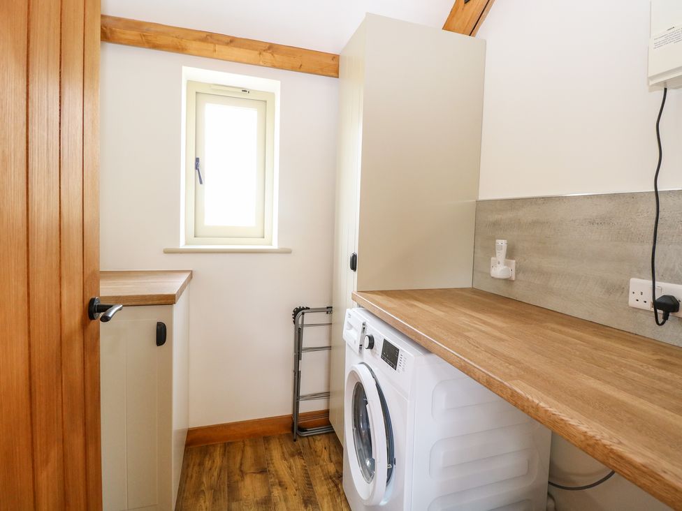 A laundry room with a washing machine wooden countertops cabinets and a small window at Cobblers Barn in Repps With Bastwick near Potter Heigham