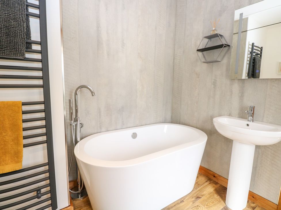 A bathroom with a freestanding bathtub sink and towel rack at Cobblers Barn in Repps With Bastwick near Potter Heigham