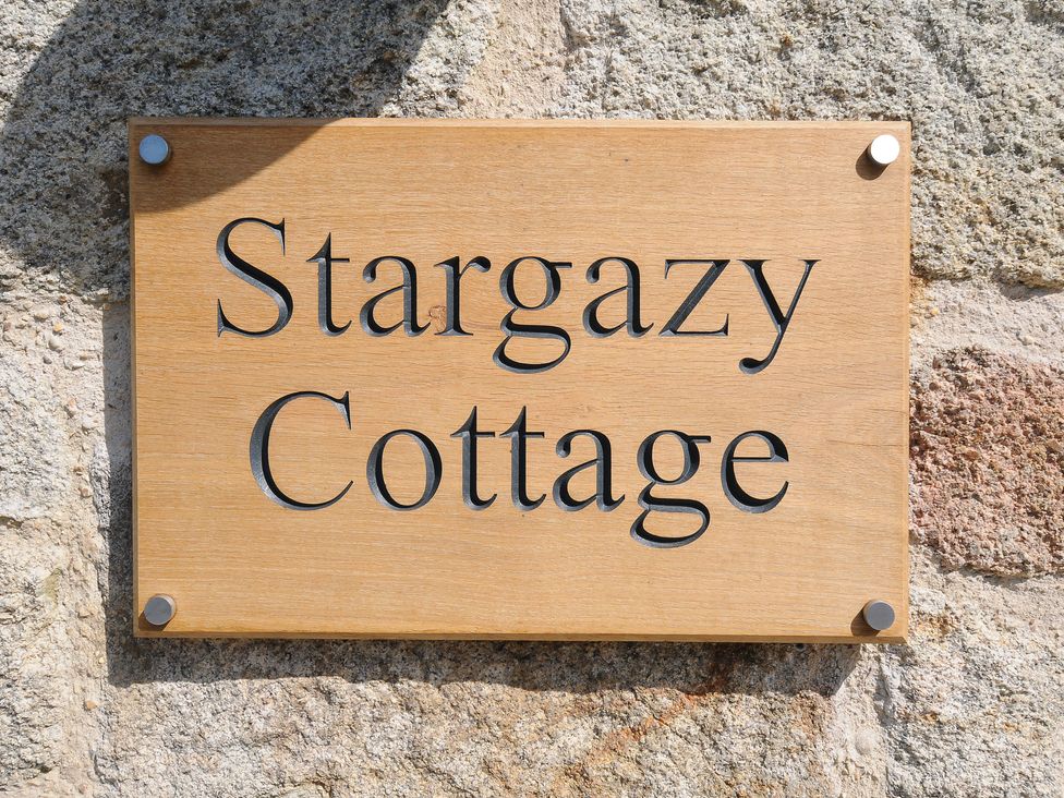 A wooden sign with the words Stargazy Cottage mounted on a stone wall at Stargazy Cottage in Praa Sands