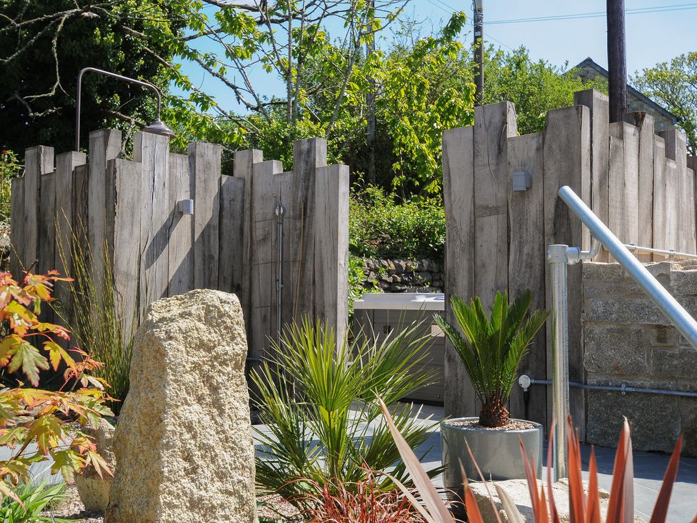 An outdoor area with wooden fencing stone steps metal railing and various plants at Stargazy Cottage in Praa Sands