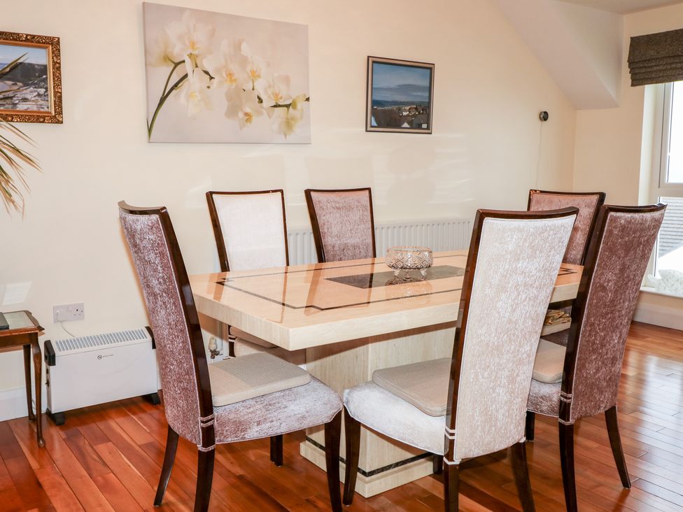 A dining room with a rectangular table and six chairs on a wooden floor at Seaview in Castlerock