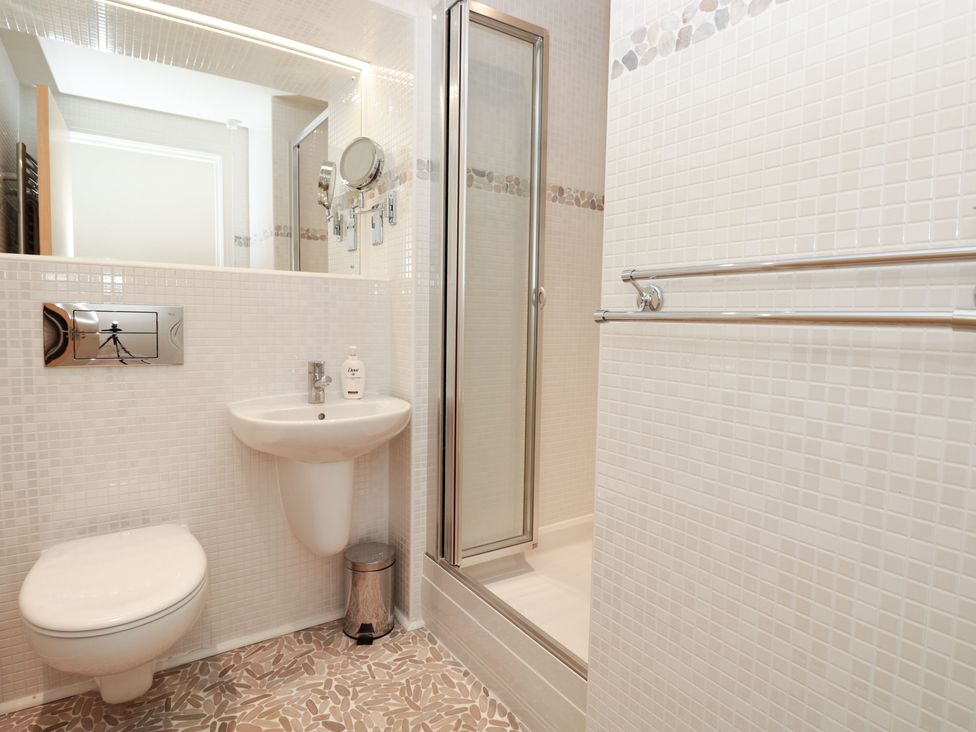 A bathroom with a wall-mounted toilet sink shower and towel rack at 7 Ocean's Edge in Thurlestone