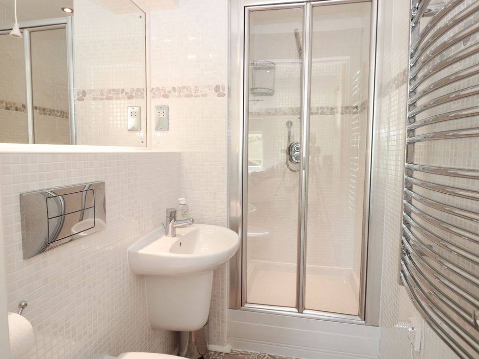 A bathroom with a sink toilet shower and towel heater at 7 Ocean's Edge in Thurlestone