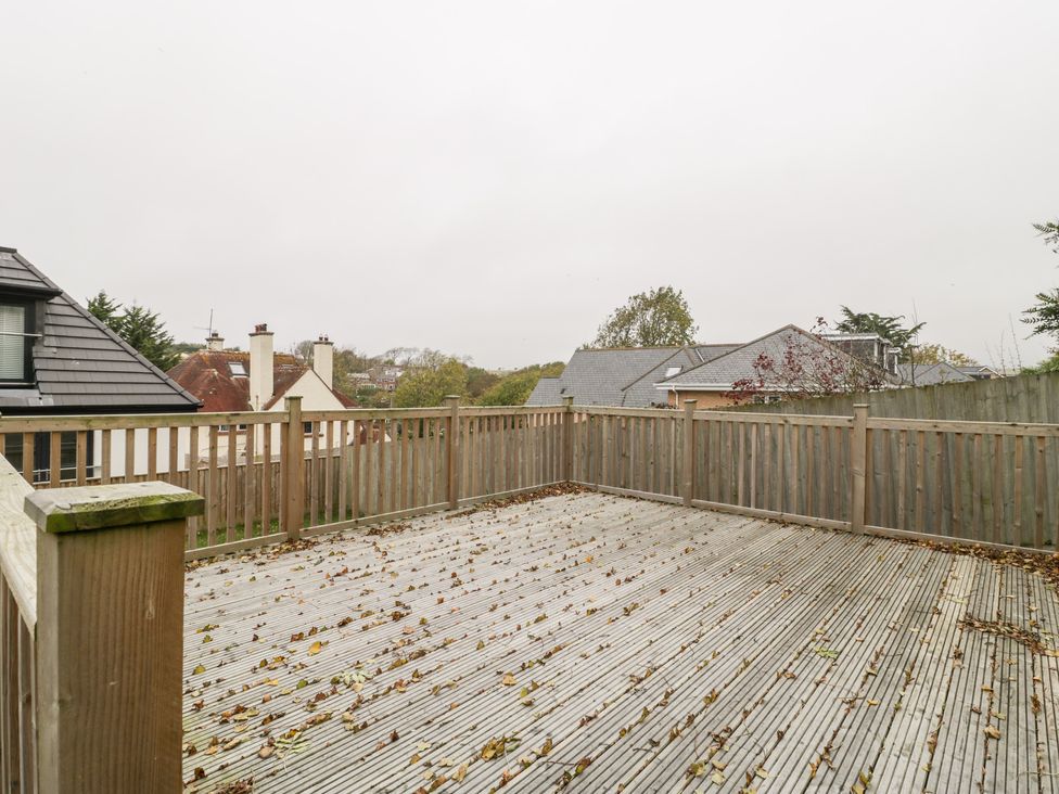 An empty wooden deck with scattered leaves and wooden railing around at Flat 2 38 Preston Road in Weymouth