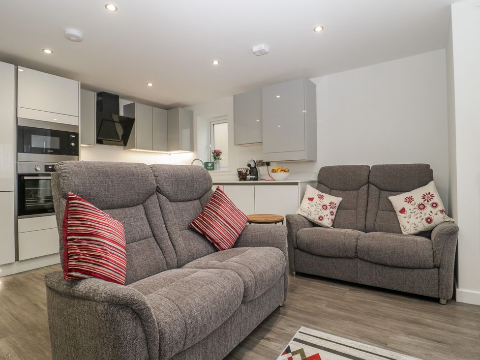 A living room with two gray sofas and a modern kitchen in the background at Flat 2 38 Preston Road in Weymouth