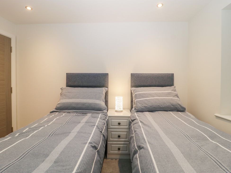 A bedroom with two single beds and a bedside table with a lamp at Flat 2 38 Preston Road Weymouth