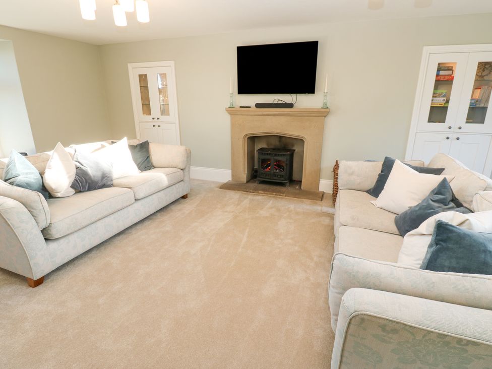 A living room with two sofas and a fireplace with a mounted television at Valley View in West Witton