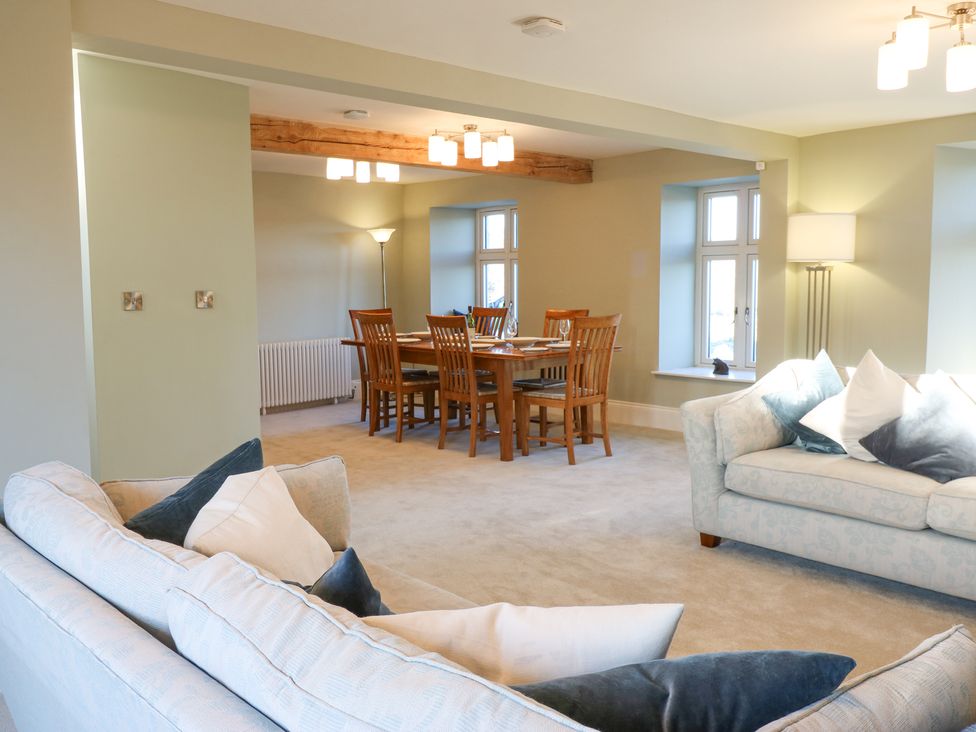 A living room with two sofas and cushions and a dining area with a wooden table and chairs at Valley View in West Witton